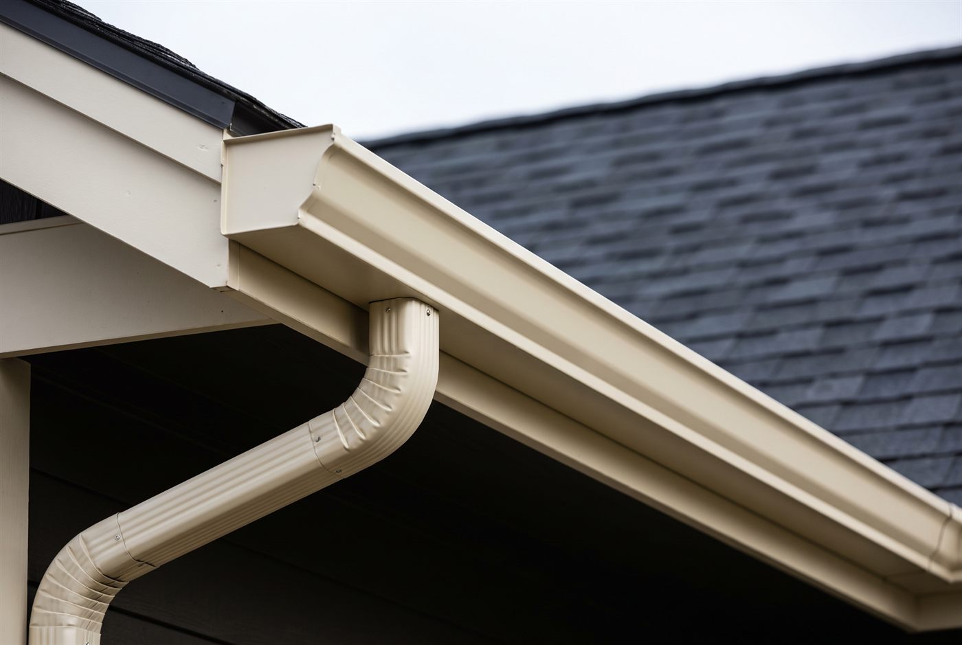 A new seamless aluminium gutter run and downspout along a residential eave